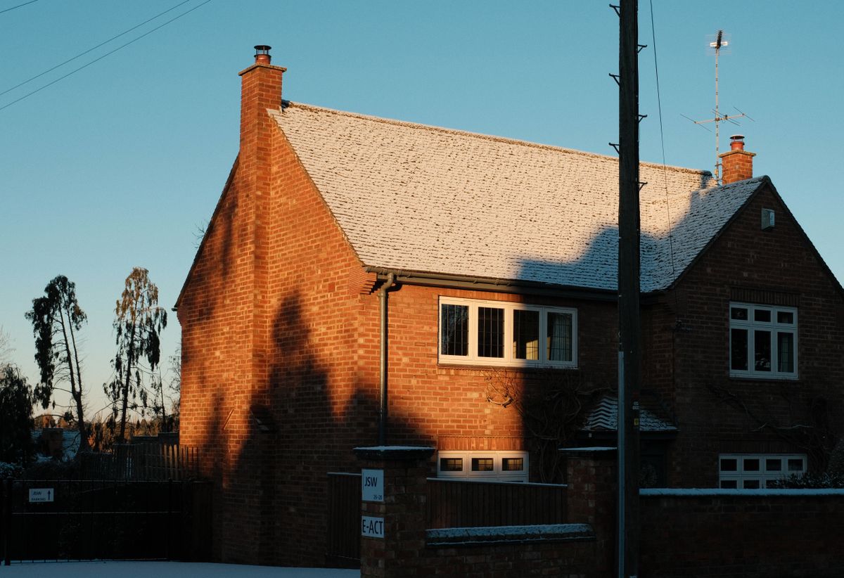 A pitched brick-house roof with a thin layer of snow
