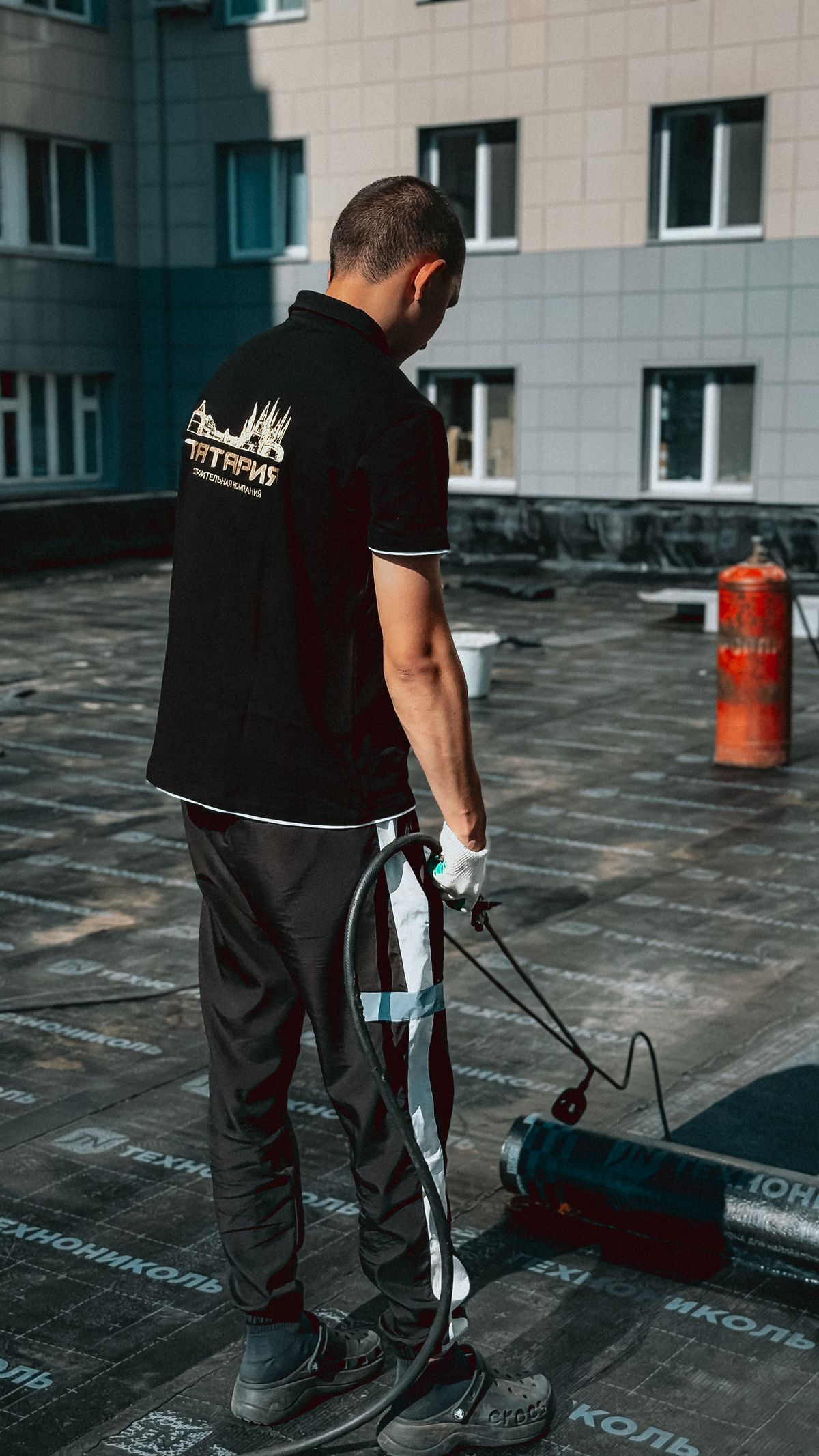 A professional working with bituminous roofing on a low-slope roof