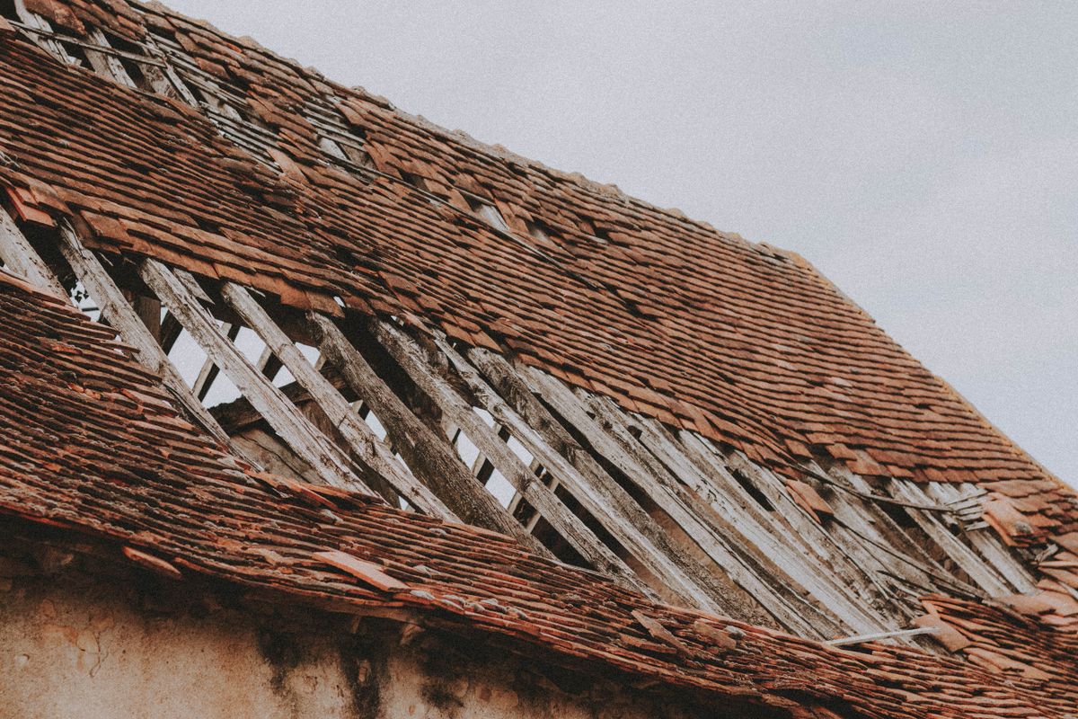 An older tile roof with missing covering and exposed supporting battens