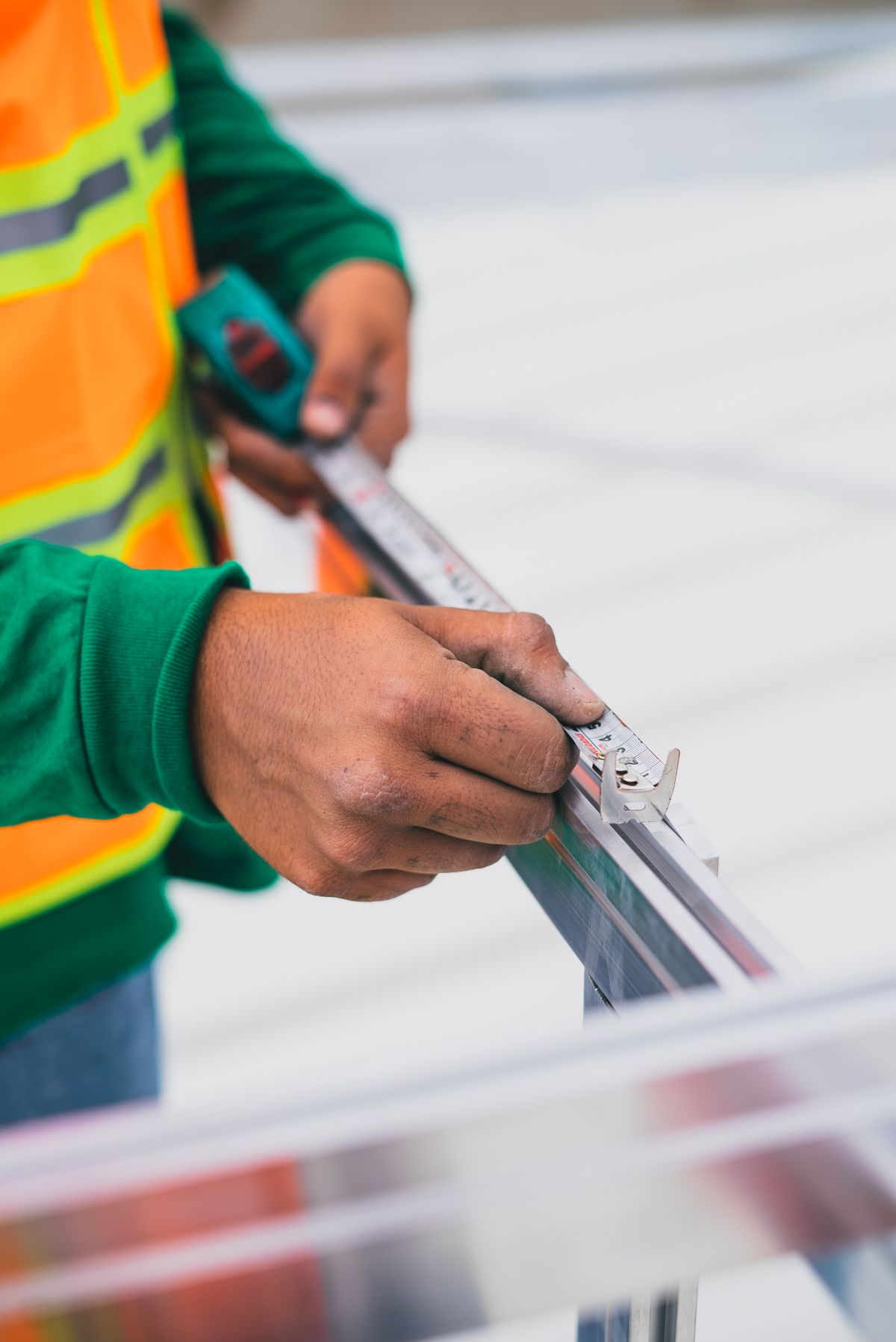 Hands measuring a construction component with a tape measure